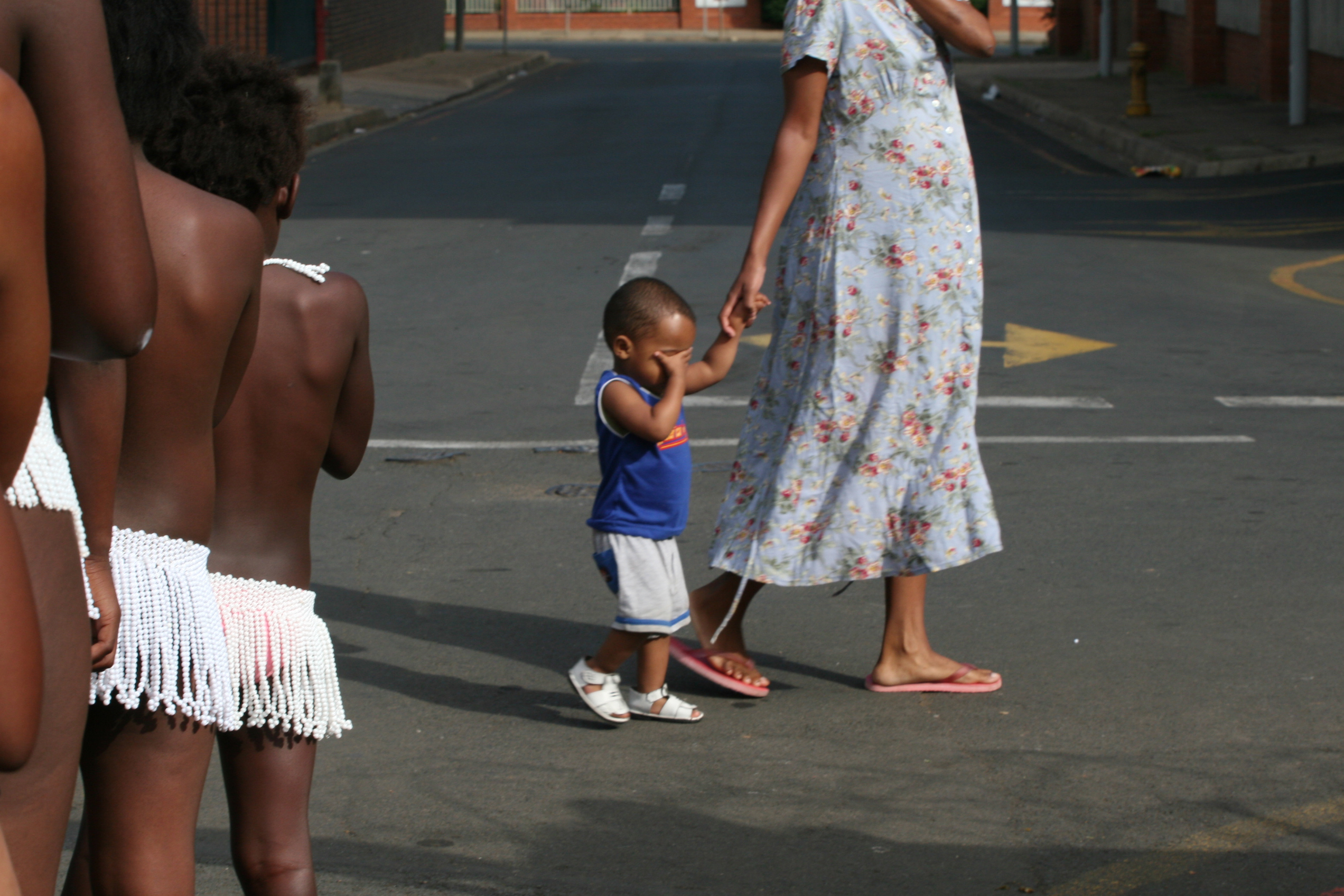 A young boy with his mother covers his eyes as he passes infront of naked girls undergoing a virginity test on sunday 18 February in Pietmaritzburtg town about 480 kilometers from Johnnesburg.There were 200 girls aged between 6 and 31 years who underwent the process and declared as virgins.Although human rights activists have been condemming this Zulu culture as demeaning and incorrect the women elders who carry it out have vowed that it must continue.They argue that it prevents the spread of HIV and also gives self esteem to those who are declared as virgins.Photo Antony Kaminju